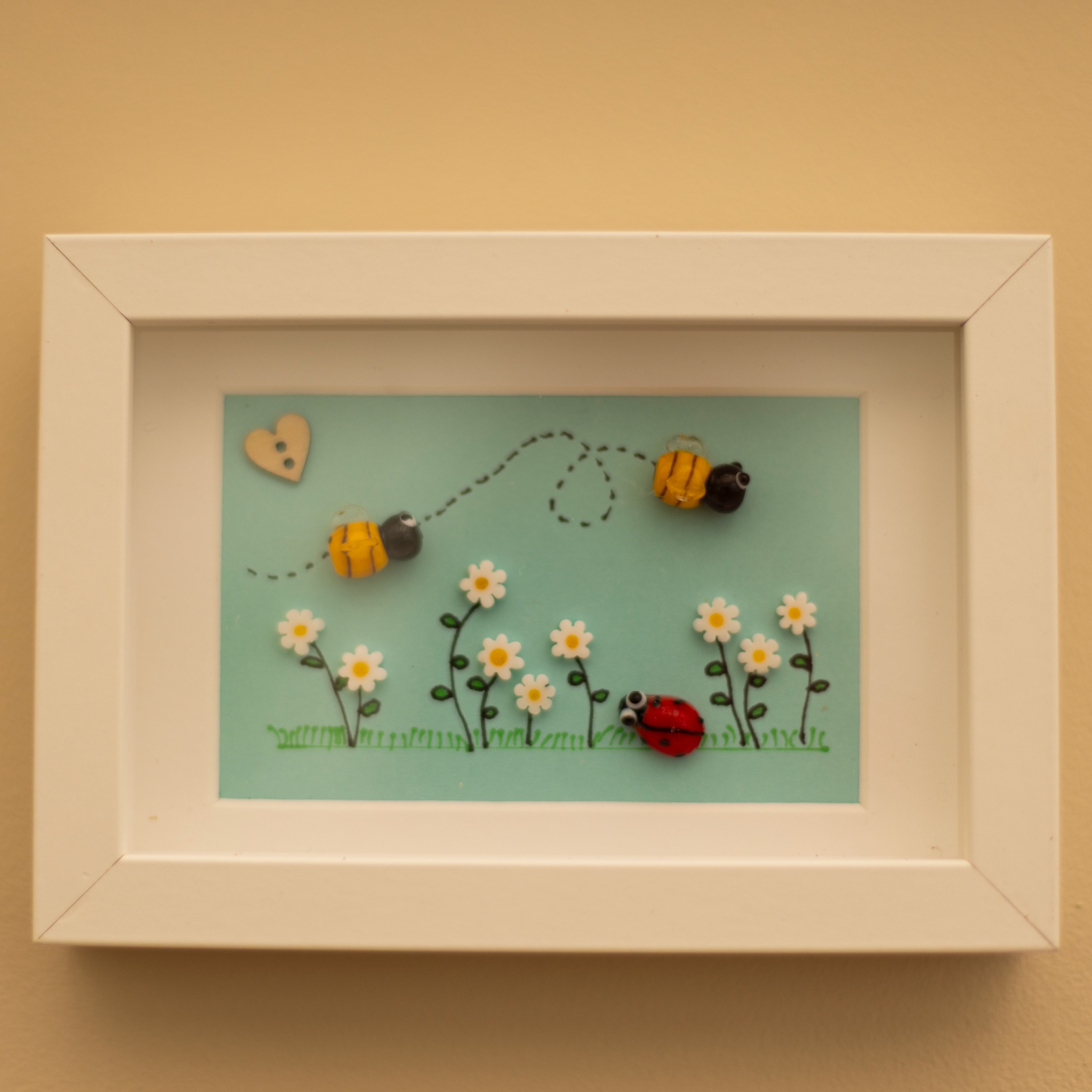 Framed bee and ladybird artwork with white frame.